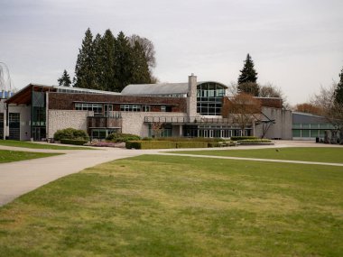 Modern bir binanın manzarası ve Burnaby, Kanada 'da ağaçları ve çiçekleri olan bir bahçe.