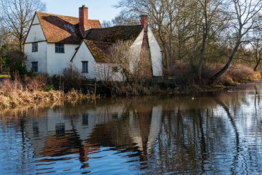 Küçük bir nehrin manzarası ve bir sonbahar günü ormanlık alanda küçük bir kırsal bina.