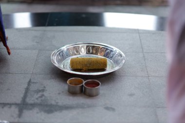 Gümüş bir kaseye yerleştirilmiş Hint Ammikal aletinin yakın çekimi.