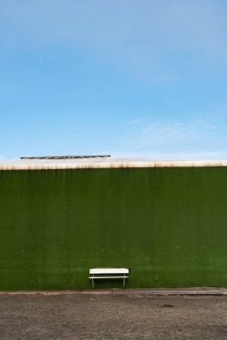 Yeşil bir duvara karşı boş bir bankın dikey çekimi.