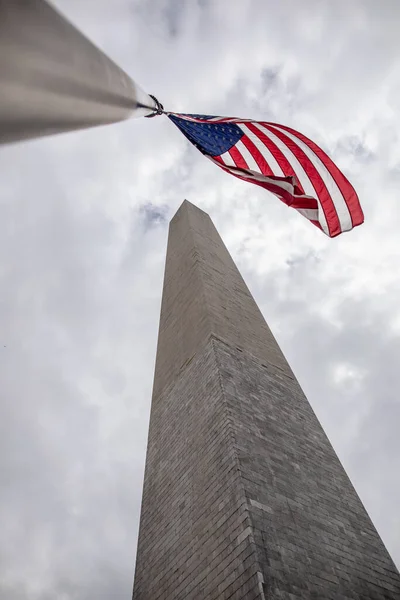 Niski Kąt Strzał Flagi Usa Obok Wieży Pod Zachmurzonym Niebem — Zdjęcie stockowe