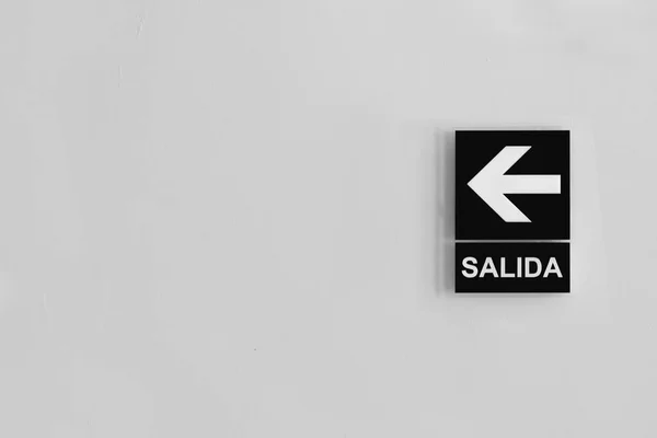 左矢印とスペイン語でグレースケール出口 Salida サイン — ストック写真