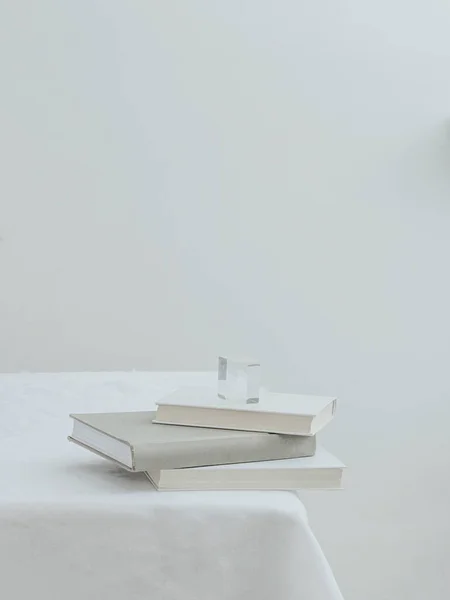 An aesthetic view of three books on a table with white tablecloth