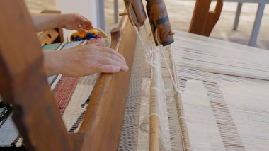 Arka planda bir dokuma makinesi ve eller