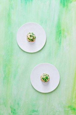 Yeşil boyalı arka planda, küçük bir porsiyon kızarmış pirincin iki tabağının üst görüntüsü.