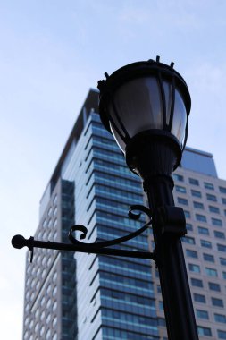 Düşük açılı bir sokak lambası ve arka planda modern çok katlı bir bina.
