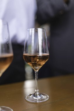 Masadaki bir bardak gül şarabının seçici odak noktası.