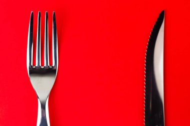 Gümüş çatal ve parlak kırmızı arka planda bir bıçak..