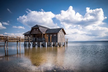 Almanya, Bavyera 'da Ammersee Gölü' nde bulutlu bir gökyüzüne karşı eski bir kayıkhane.