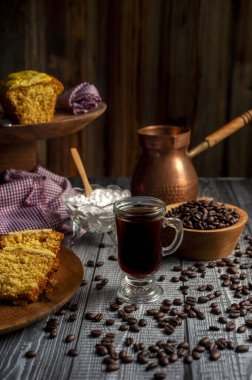 Kahve çekirdekleri, kahve fincanları, tahta tabakta pasta dilimleri.