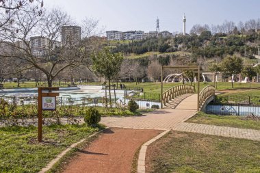 İstanbul 'da yeşil çimenli, ağaçlı ve arka planda açık gökyüzü binalı bir park