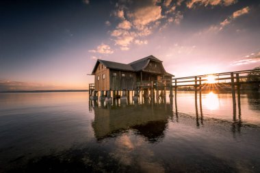 Almanya 'nın Bavyera şehrinde gün batımına karşı Ammersee Gölü üzerinde güzel bir kayıkhane manzarası
