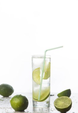 Beyaz arka planda birkaç limonun yanında bir bardakta taze limon suyu..