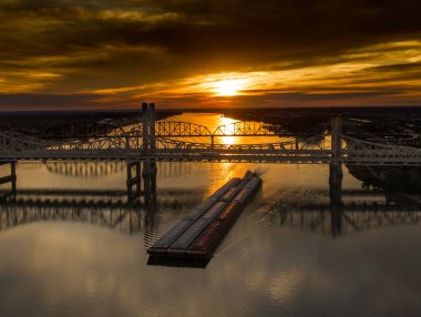 Gün batımında köprüden geçen bir mavna.