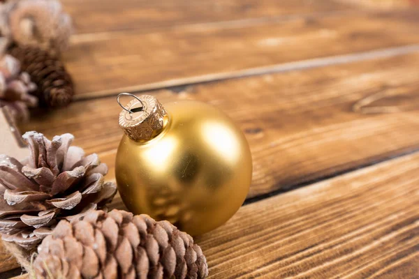 Tiro Close Uma Bola Natal Plástico Pinhas Uma Mesa Madeira — Fotografia de Stock