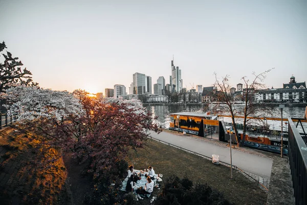 Grupp Vänner Gör Picknick Parken Nära Floden Vid Solnedgången Storstaden — Stockfoto