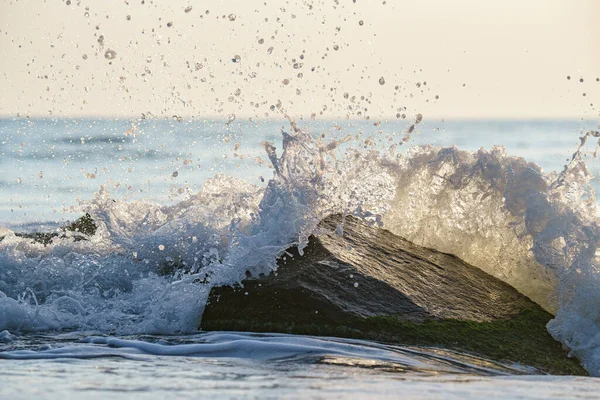 海に大きな岩を打つ水ながら作られたスプラッシュの瞬間の美しいショット — ストック写真