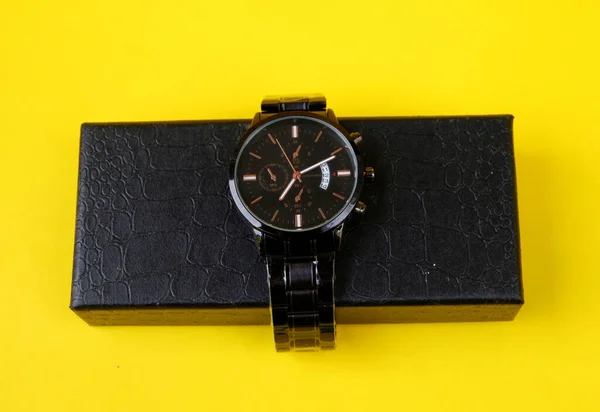 黄色の背景を持つ黒のギフトボックスに高級腕時計のクローズアップショット — ストック写真