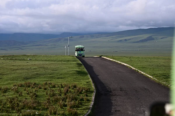 Piękne Ujęcie Autobusu Jadącego Asfaltową Drogą Przeciwko Zielonemu Krajobrazowi Zachmurzonemu — Zdjęcie stockowe