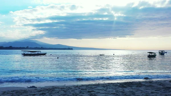 Gün batımında kumlu bir sahilin yakınına park edilmiş tekneler.