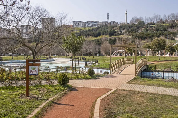 İstanbul 'da yeşil çimenli, ağaçlı ve arka planda açık gökyüzü binalı bir park