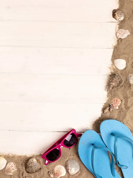 Рама Солнцезащитными Очками Песком Моллюсками Шлепанцами Белом Деревянном Фоне — стоковое фото