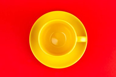 Kırmızı zemin üzerinde bir tabakta seramik sarı çay fincanı..