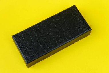 Sarı arka planda siyah bir hediye kutusunun yakın çekimi.