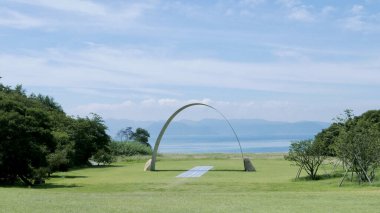 Açık havada güneşli bir yaz günü soyut bir heykel mavi gökyüzünün altında yeşilliklerle çevrili