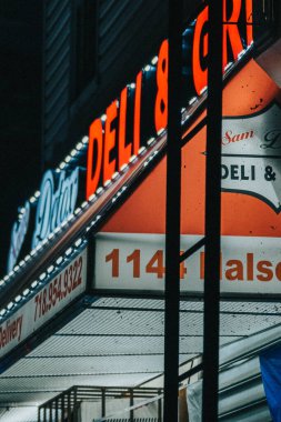 Geceleyin Brooklyn 'de bir şarküteri tabelası ve neon ışıklarının dikey çekimi.
