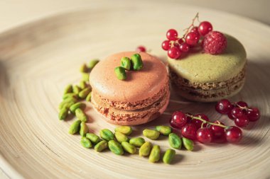 A closeup shot of beautiful macaroons with berries and pistachio