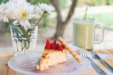 Bir dilim turtaya yakın plan. Çiçekli bir tabakta çilek.