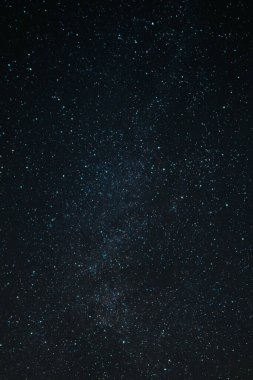 Gece yarısı yıldızlı ve sütlü karanlık gökyüzünün dikey görüntüsü