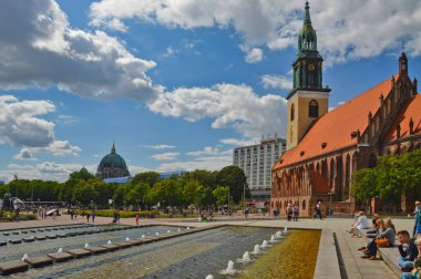 Berlin, Almanya 'da güneşli bir günde Alexander Platz' da dinlenen turistlerin güzel bir görüntüsü..
