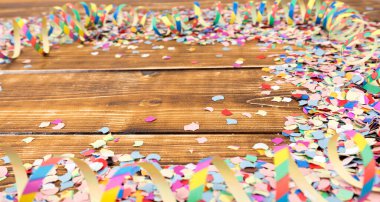 Ahşap bir masanın üzerinde bir yığın renkli konfeti ve flamalar.