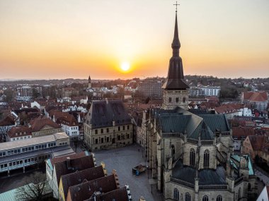 Eski binalarla çevrili tipik bir Avrupa meydanının ve gün batımında bir katedralin hava görüntüsü..
