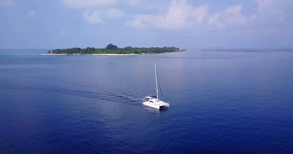 An aerial view of white sailing boat in the blue ocean with island in the background in Asia