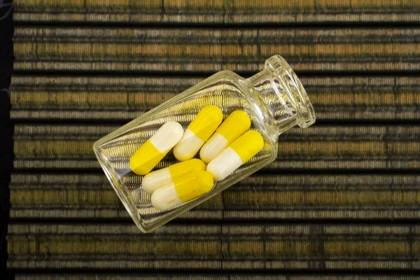 Вид Сверху Прозрачную Бутылку Желтыми Белыми Таблетками Полосатой Ткани — стоковое фото