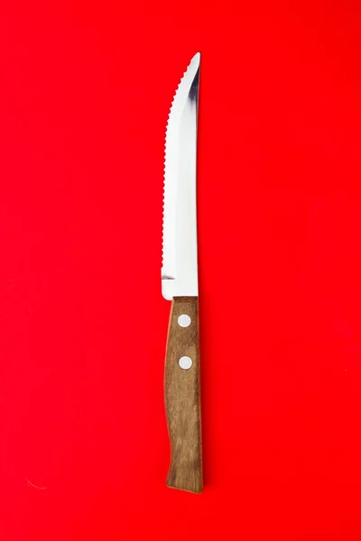 Parlak Kırmızı Arka Planda Gümüş Tereyağı Bıçağının Dikey Üst Çekimi — Stok fotoğraf
