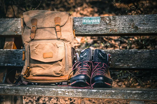 复古背包和远足靴在木制长椅上 远足用具上的照片 — 图库照片