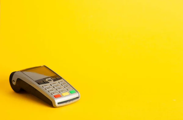 A closeup of an electronic payment terminal isolated on the left side of the yellow background