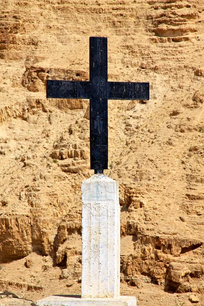 A closeup of a black cross near a mountain