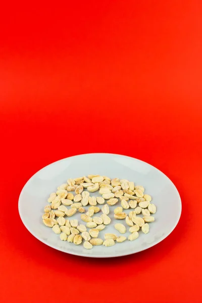 Sebuah Gambar Vertikal Dari Sepiring Kacang Asin Pada Permukaan Merah — Stok Foto