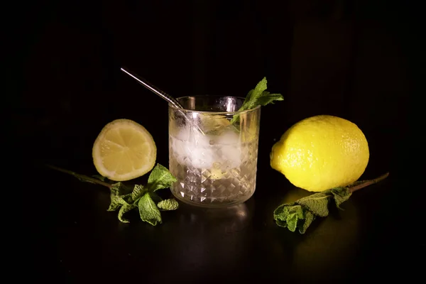 一个特写镜头柠檬薄荷杜松子酒鸡尾酒与柠檬和半分离的黑色背景 — 图库照片