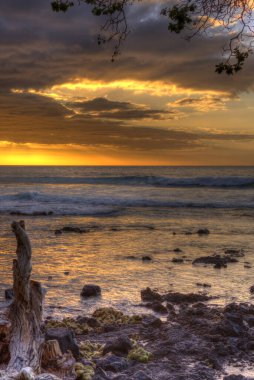 Sahilde gökyüzünde gün batımının dikey görüntüsü.