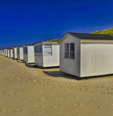 Mavi gökyüzüne karşı beyaz tahta kulübelerin dikey görüntüsü.