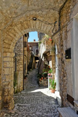 İtalya 'nın orta kesimindeki tarihi Sermoneta kasabasında dar bir sokakta kemerli bir geçitin dikey görüntüsü.