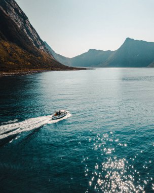 Norveç, Senja Denizi 'nde arka planda dağ katmanları olan bir yelkenli görüntüsü.