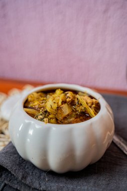 Sarımsak şekilli beyaz bir kâse üzerindeki yahni çorbasının sığ odağı.