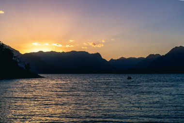 Yaz mevsiminde gün batımında sakin bir deniz ve adaların silueti